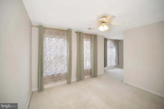 an empty room with a chandelier fan and a bathroom