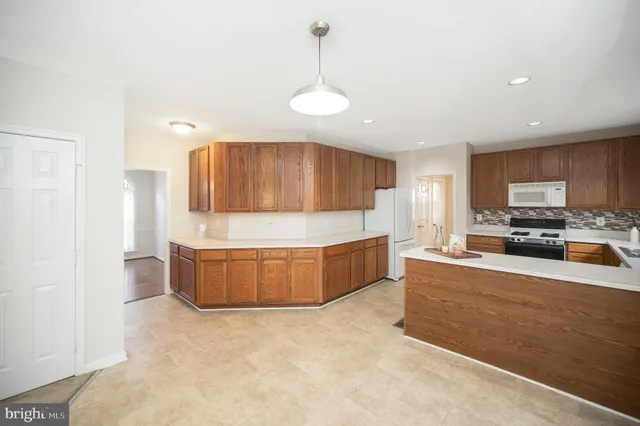 a large kitchen with stainless steel appliances a large counter top a stove and a refrigerator