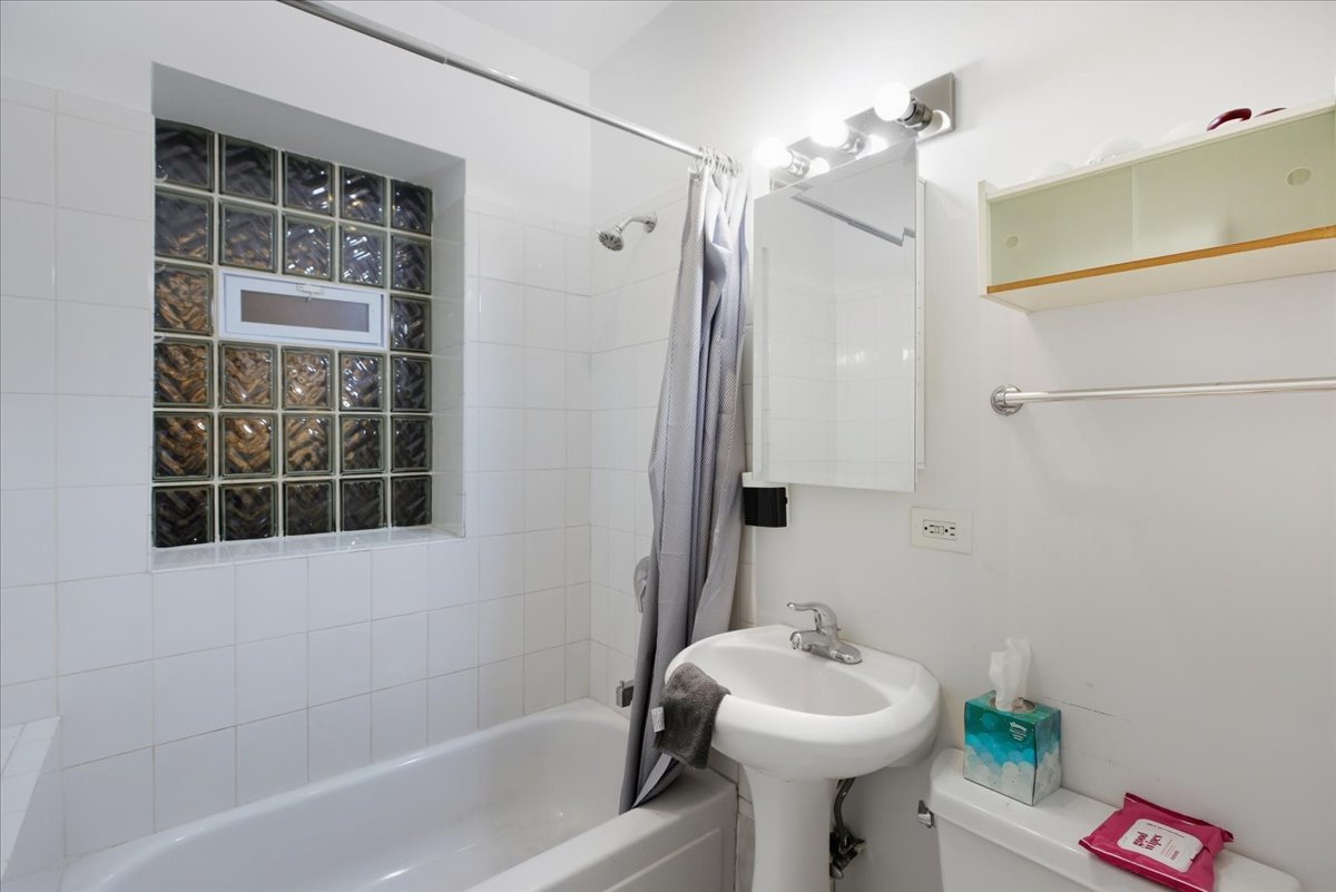 4055 North Spaulding Avenue, Unit 1 Chicago, IL 60618 - Photo 7 of 13 a bathroom with a sink mirror and a bathtub