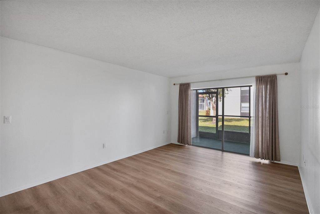 3231 South Beneva Road, Unit 103 Sarasota, FL 34232 - Photo 5 of 31 a view of an empty room with wooden floor and a window