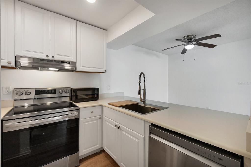 3231 South Beneva Road, Unit 103 Sarasota, FL 34232 - Photo 10 of 31 a kitchen with granite countertop white cabinets stainless steel appliances and a sink