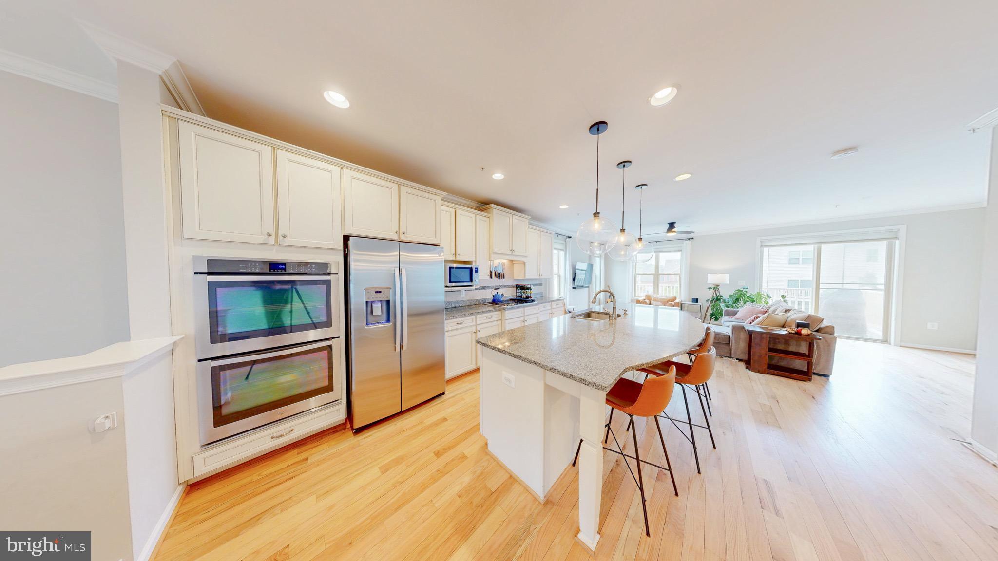 13227 Deer Highlands Way Silver Spring, MD 20906 - Photo 3 of 20 a kitchen with stainless steel appliances kitchen island granite countertop a refrigerator a stove a sink a dining table and chairs with wooden floor