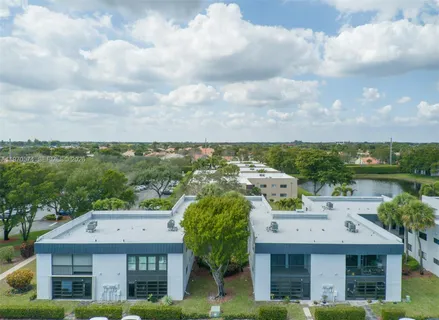 a view of a white house with a big yard and potted plants