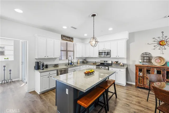 a kitchen with a stove a kitchen island white cabinetry and wooden floor