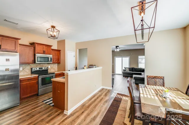 a kitchen view of a dining table chairs stove and cabinets