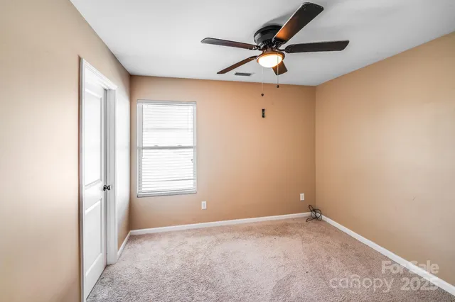 an empty room with a window and a fan