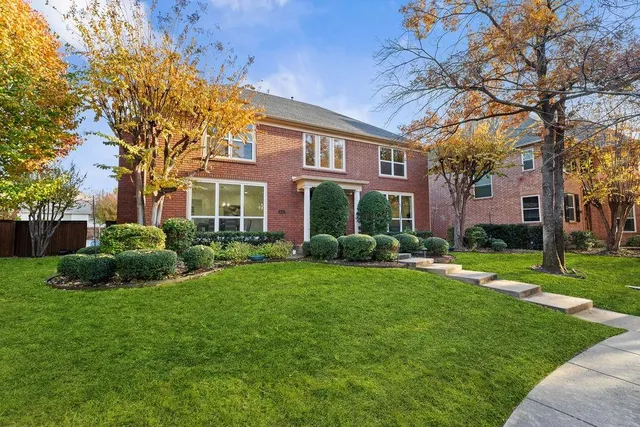 a view of a brick house with a big yard and large trees