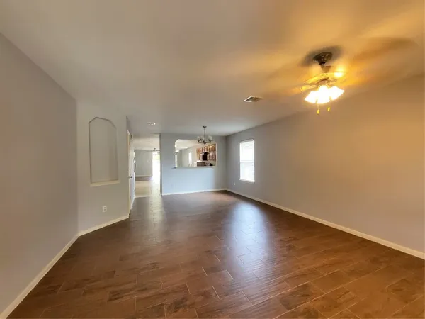 a view of empty room with wooden floor and fan