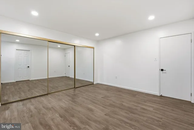 an empty room with wooden floor and mirror