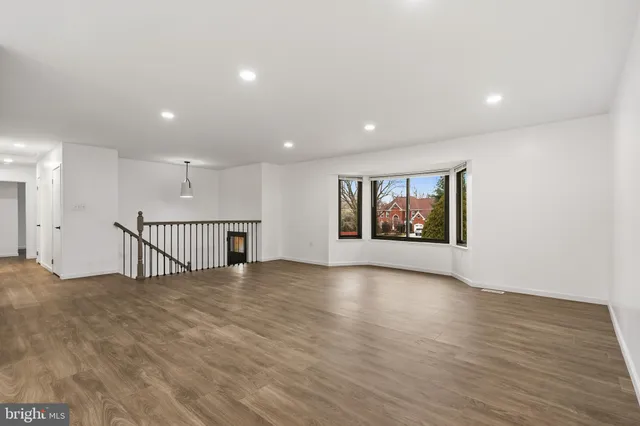 a view of an empty room with wooden floor and window