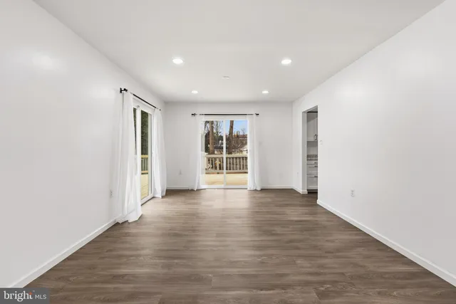 a view of an empty room with wooden floor and windows