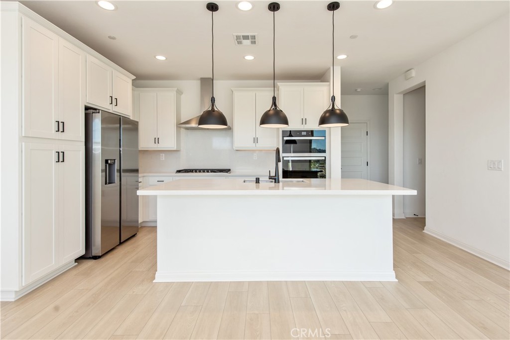 781 Cornelia Way Rancho Mission Viejo, CA 92694 - Photo 8 of 24 a kitchen with stainless steel appliances a refrigerator a oven a stove and a wooden floors