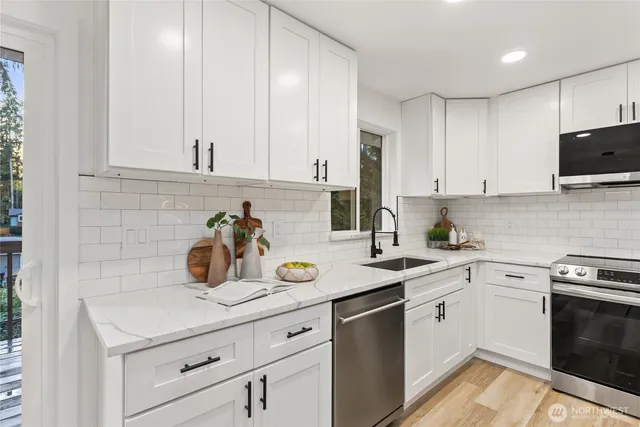 a kitchen with a sink dishwasher and white cabinets with wooden floor