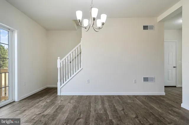 a view of a hallway with wooden floor and chandelier