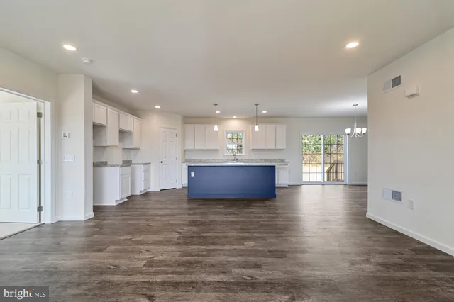 a view of kitchen with kitchen island a sink wooden floor and a refrigerator