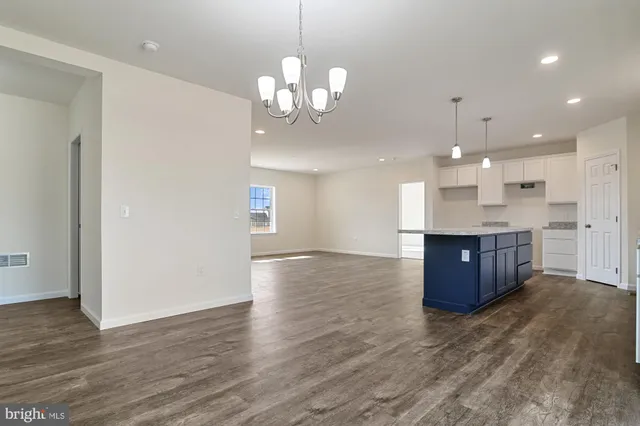 a large kitchen with a chandelier and wooden floors