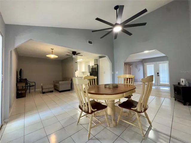 a dining room with furniture and a chandelier fan