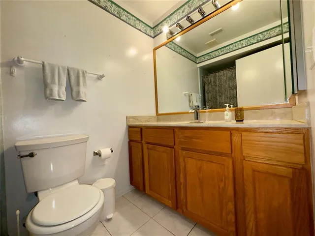 a bathroom with a granite countertop toilet sink and mirror