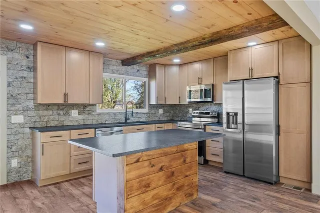 a kitchen with stainless steel appliances granite countertop a refrigerator a sink a stove and a microwave