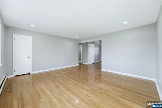 a view of an empty room with wooden floor and closet