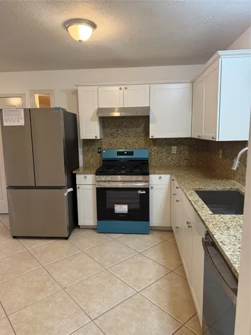 a kitchen with granite countertop a stove top oven and cabinets