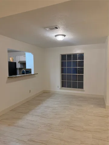 a view of an empty room with a window and a kitchen