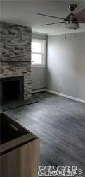 a view of an empty room with wooden floor and a fireplace