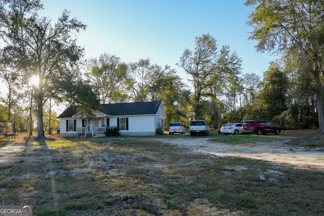 a view of a house with a yard and large trees