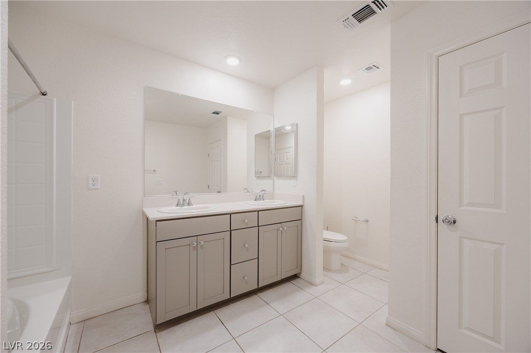 5927 Coja Street Las Vegas, NV 89113 - Photo 31 of 32 Bathroom with double vanity, tile patterned flooring, toilet, and baseboards