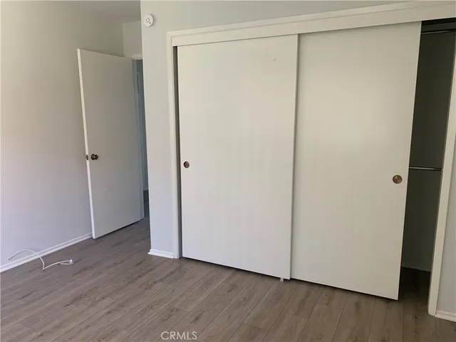 a view of an empty room with wooden floor and closet