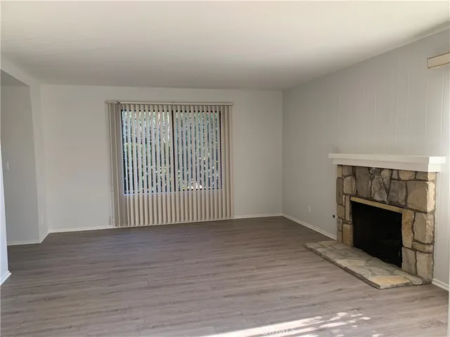 an empty room with wooden floor and fireplace