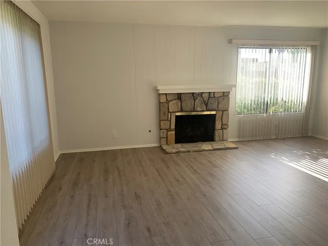 an empty room with wooden floor fireplace and windows