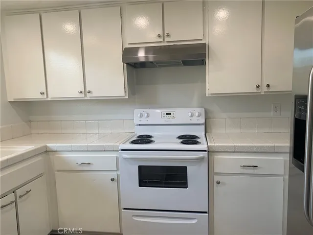 a kitchen with granite countertop white cabinets and white appliances