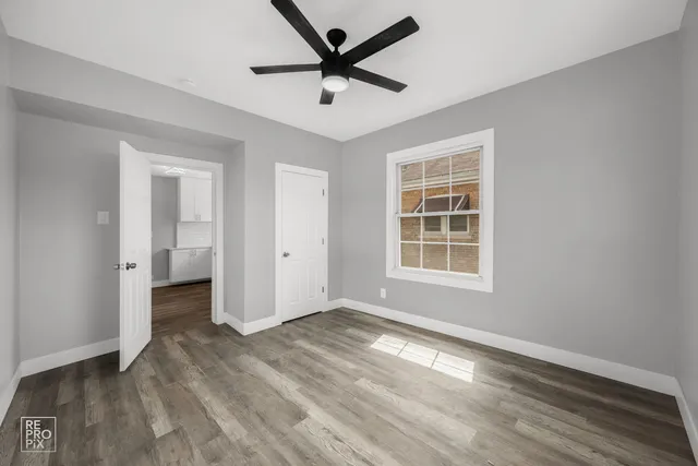 a view of empty room with wooden floor and ceiling fan