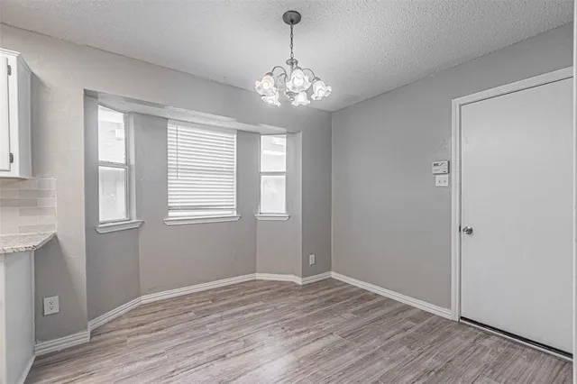 a view of an empty room with wooden floor and windows