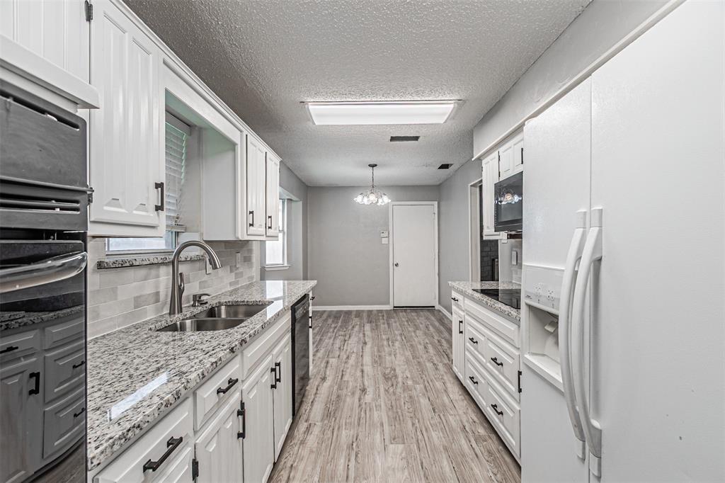 2435 Old Mill Road Dallas, TX 75287 - Photo 19 of 30 a kitchen with granite countertop a sink stove and refrigerator