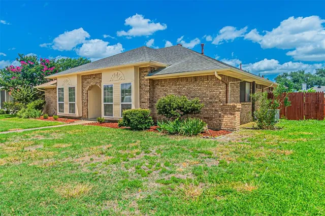 a view of a house with brick walls and a yard with plants