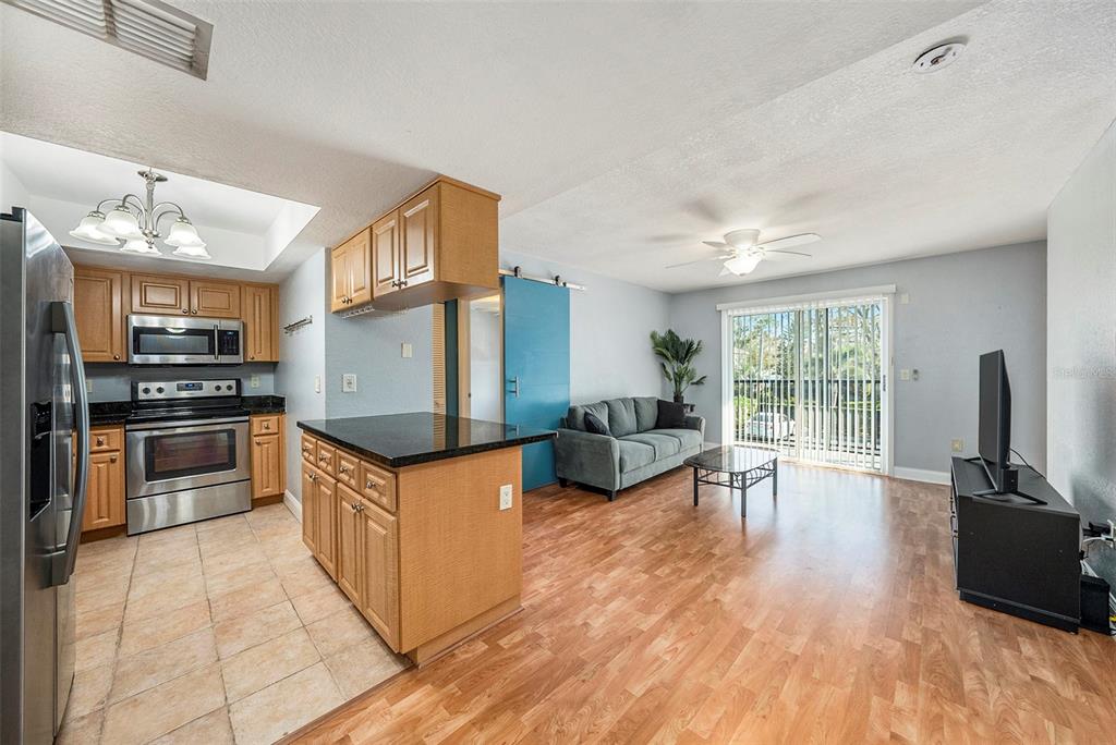 3711 West Iowa Avenue, Unit 214 Tampa, FL 33611 - Photo 2 of 29 a kitchen with granite countertop a stove top oven a sink dishwasher a dining table and chairs with wooden floor