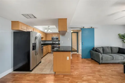 a large living room with stainless steel appliances kitchen island granite countertop a refrigerator and a stove top oven