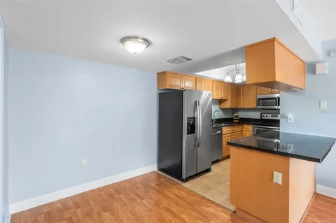 a kitchen with stainless steel appliances granite countertop a refrigerator a stove and a sink with wooden cabinets