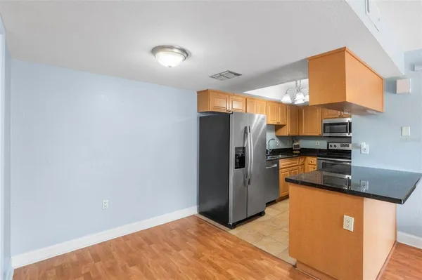 a kitchen with stainless steel appliances granite countertop a refrigerator a stove and a sink with wooden cabinets