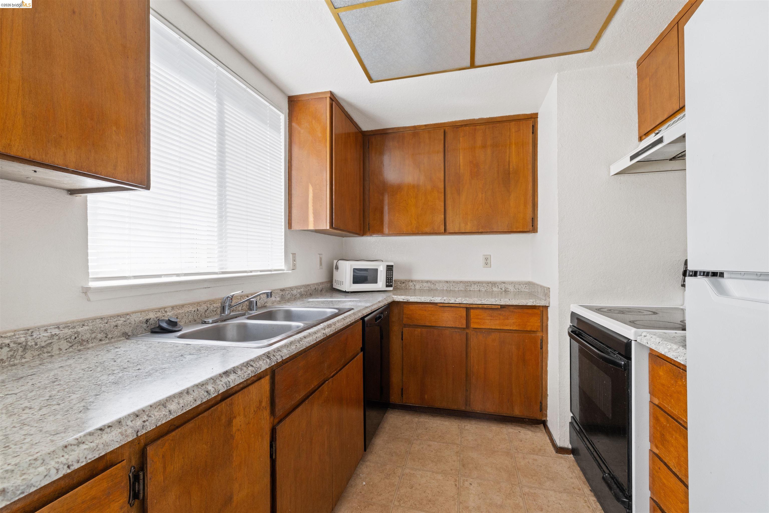 1151 Chadwick Circle Bay Point, CA 94565 - Photo 6 of 23 Kitchen featuring wood cabinetry, light-toned countertops, a double basin stainless steel sink, and a white refrigerator