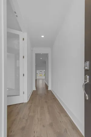 a view of a hallway with wooden floor and a bathroom
