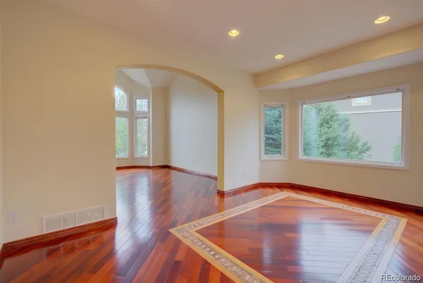 an empty room with wooden floor and windows
