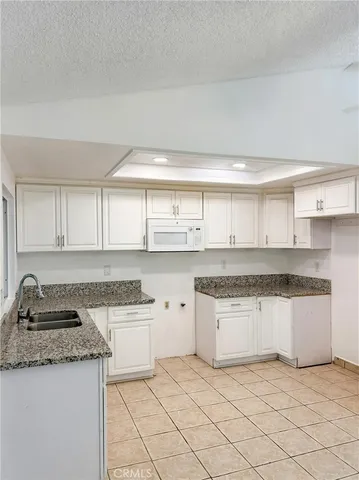 a kitchen with granite countertop white cabinets and white appliances