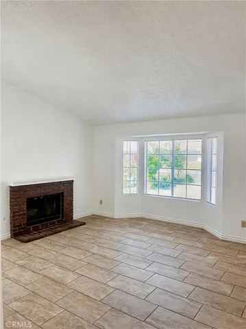 a view of an empty room with a fireplace and a window