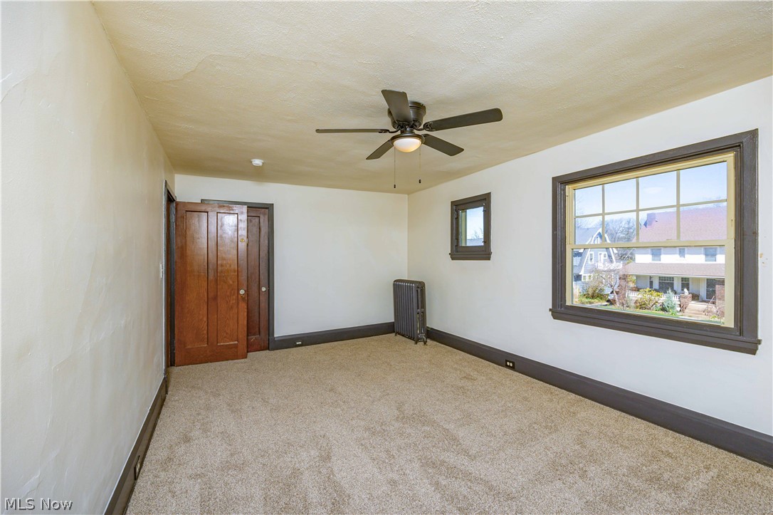 3254 Redwood Road Cleveland Heights, OH 44118 - Photo 35 of 49 Empty room featuring ceiling fan, radiator, and light colored carpet
