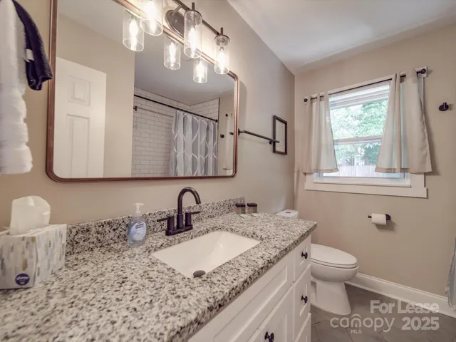 a bathroom with a granite countertop sink a toilet and a mirror