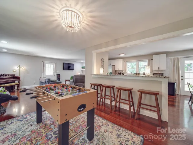 a dining room with wooden floor a chandelier a wooden table and chairs