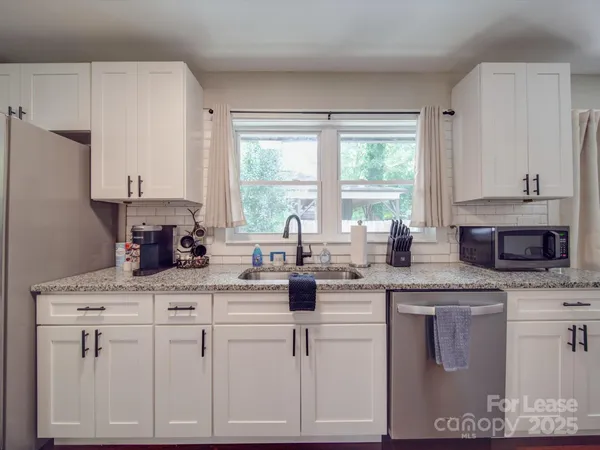 a kitchen with white cabinets and window